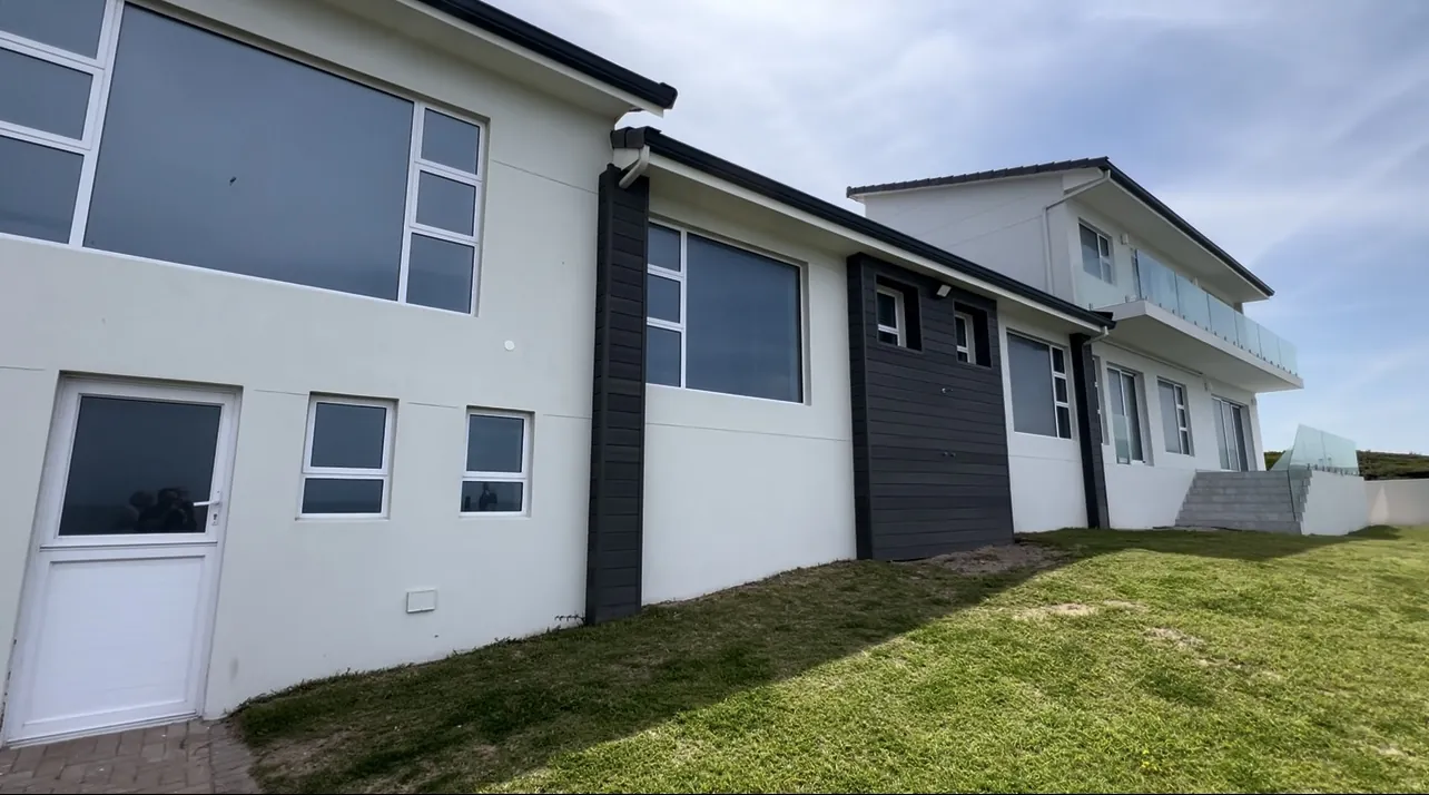 Side view of the restored Bayview home with new windows and dark cladding panels
