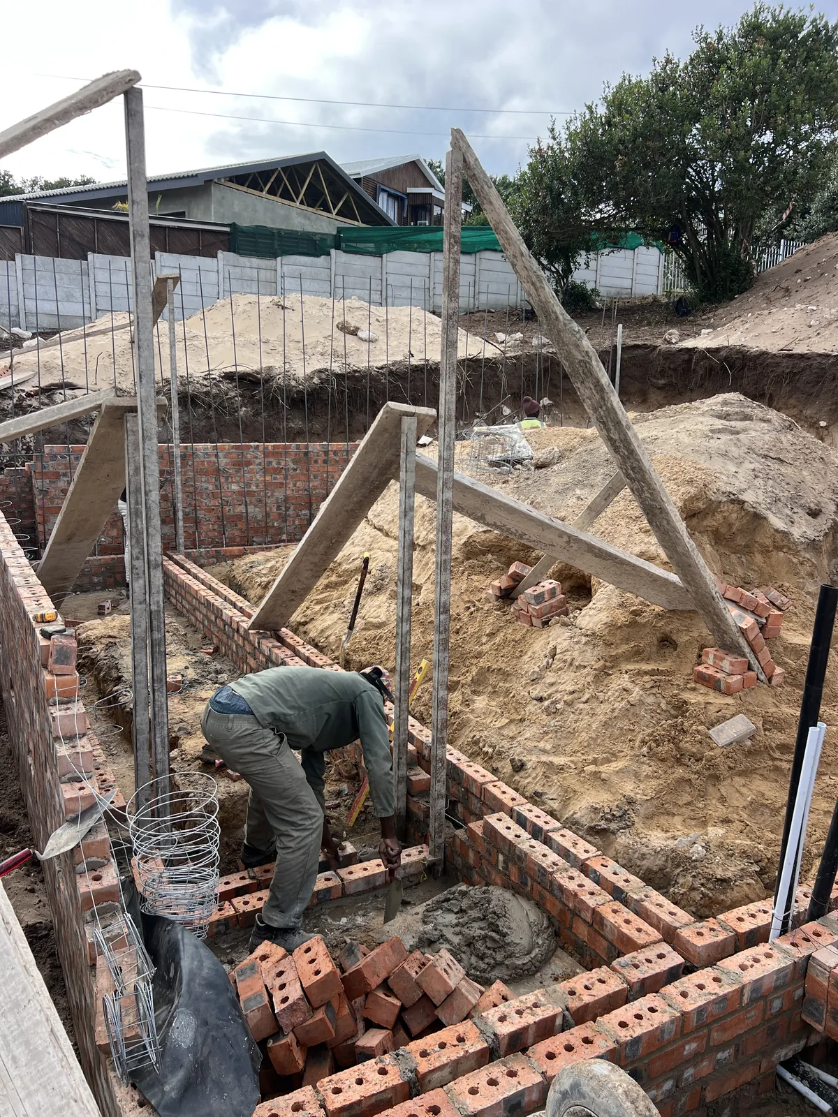 Foundation brickwork going up, with profiles set up for the walls