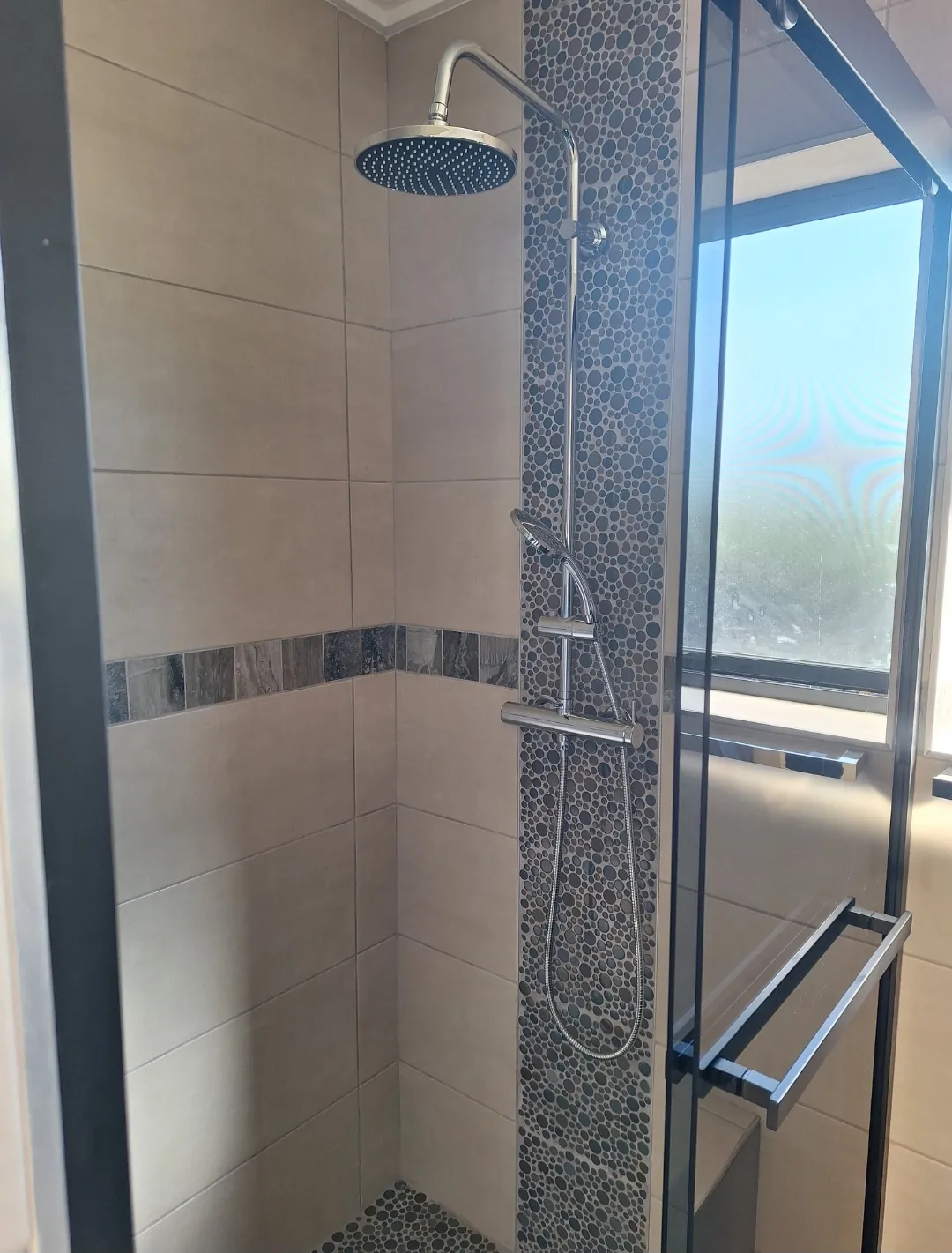 Rain shower against a pebble mosaic feature strip