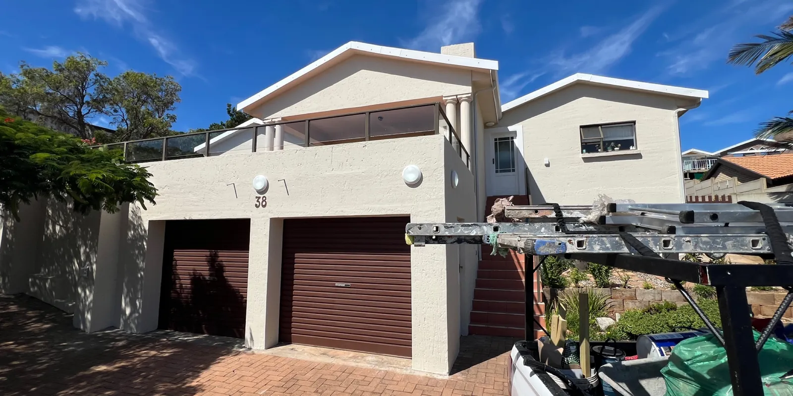 House Rooiels after repainting: off-white walls and dark brown garage doors