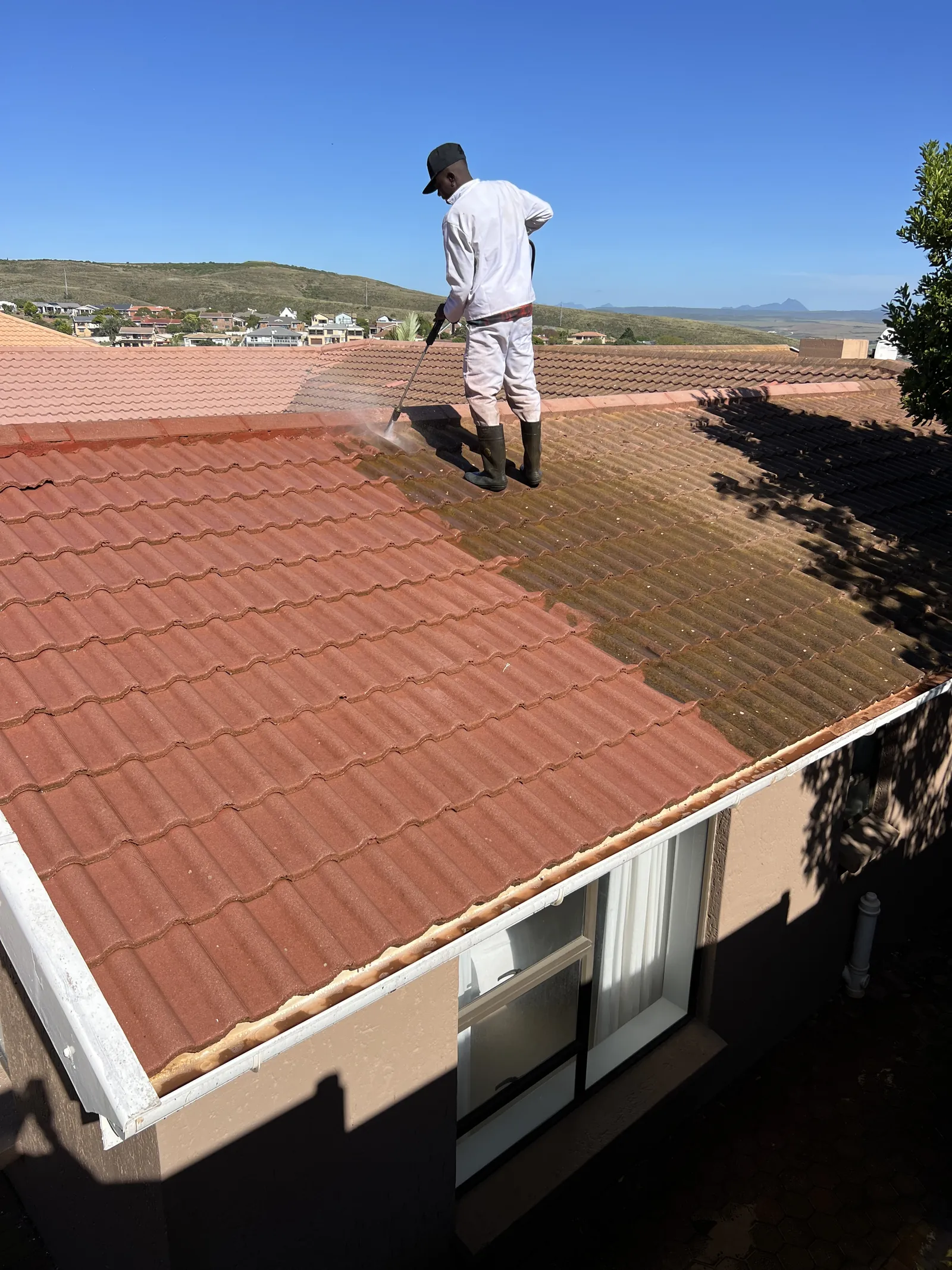 High-pressure washing the roof tiles to remove algae and dirt