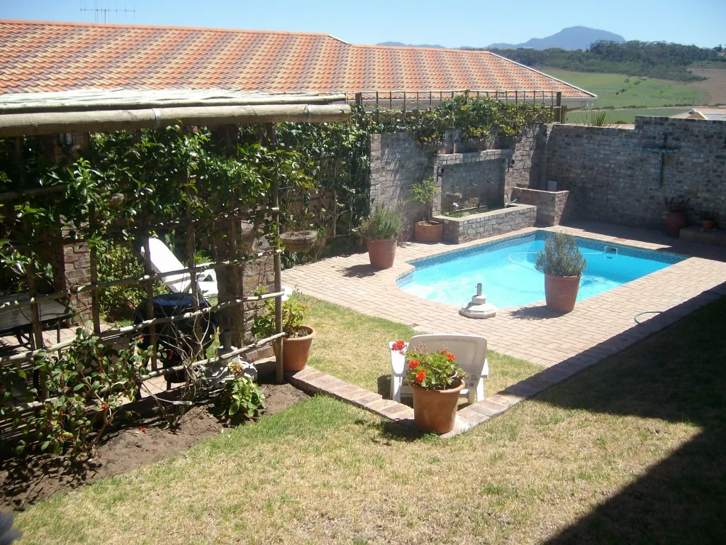 Back garden with pool, brick walls and pergola, with the mountains behind